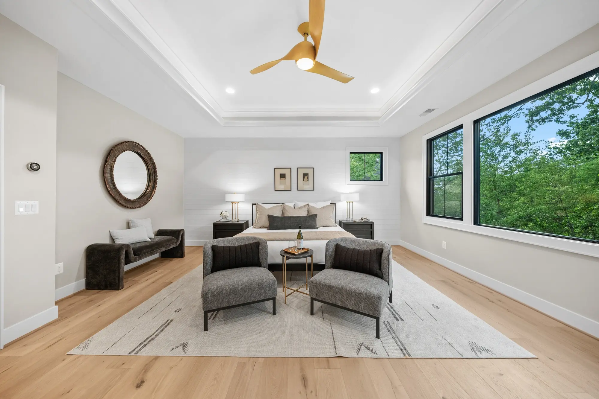 Spacious master bedroom with tray ceiling, ceiling fan, and modern staging