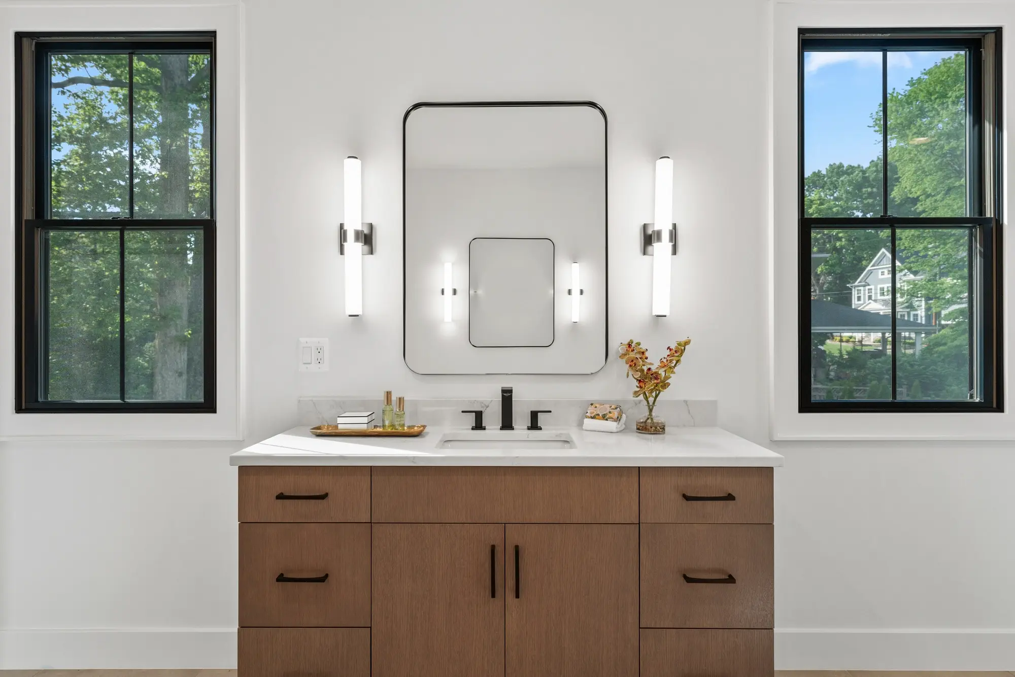 Master bathroom vanity with marble countertop, black fixtures, and modern sconce lighting