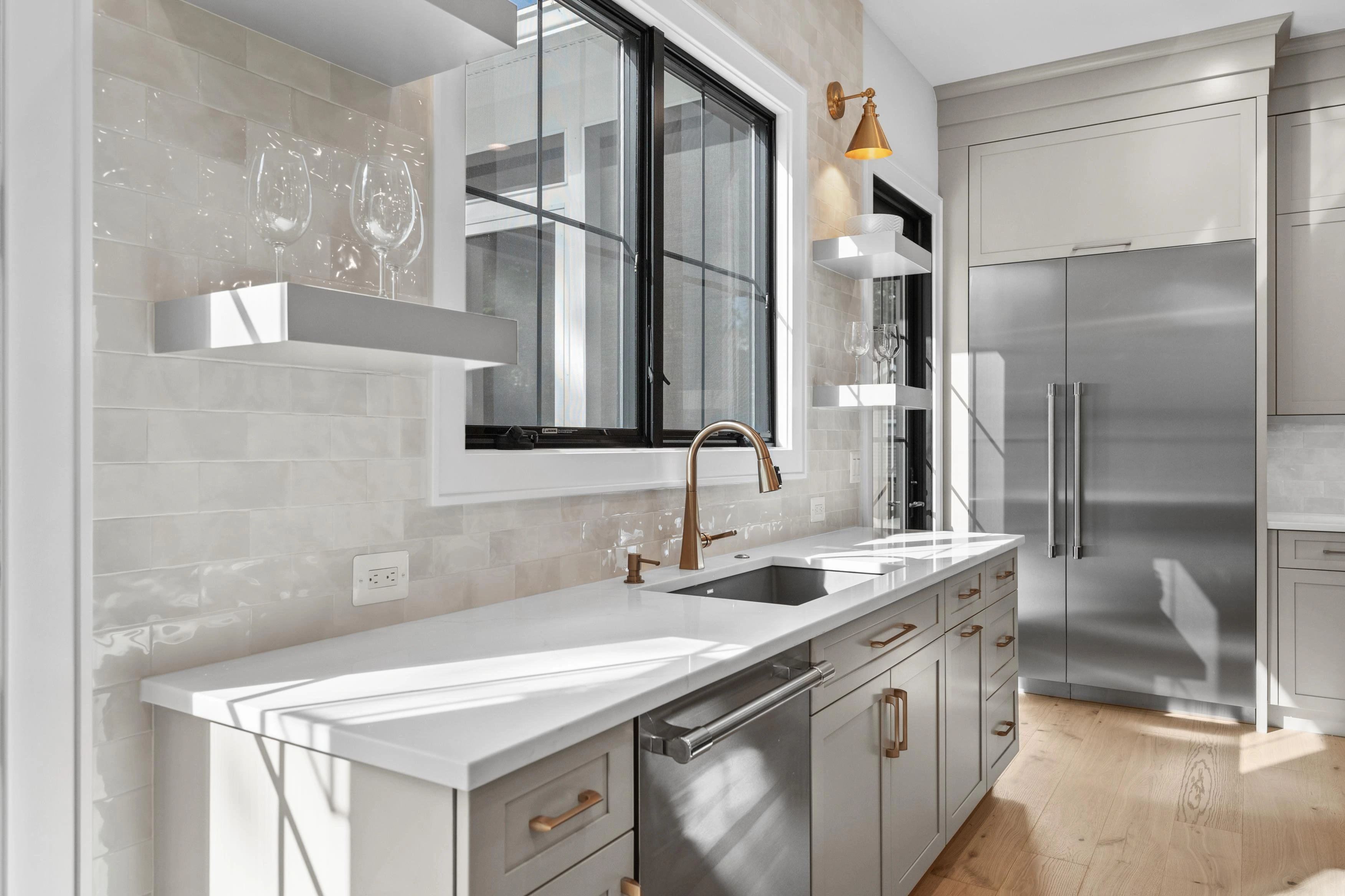 Kitchen detail showing zellige tile backsplash, brass sconces, and floating shelves