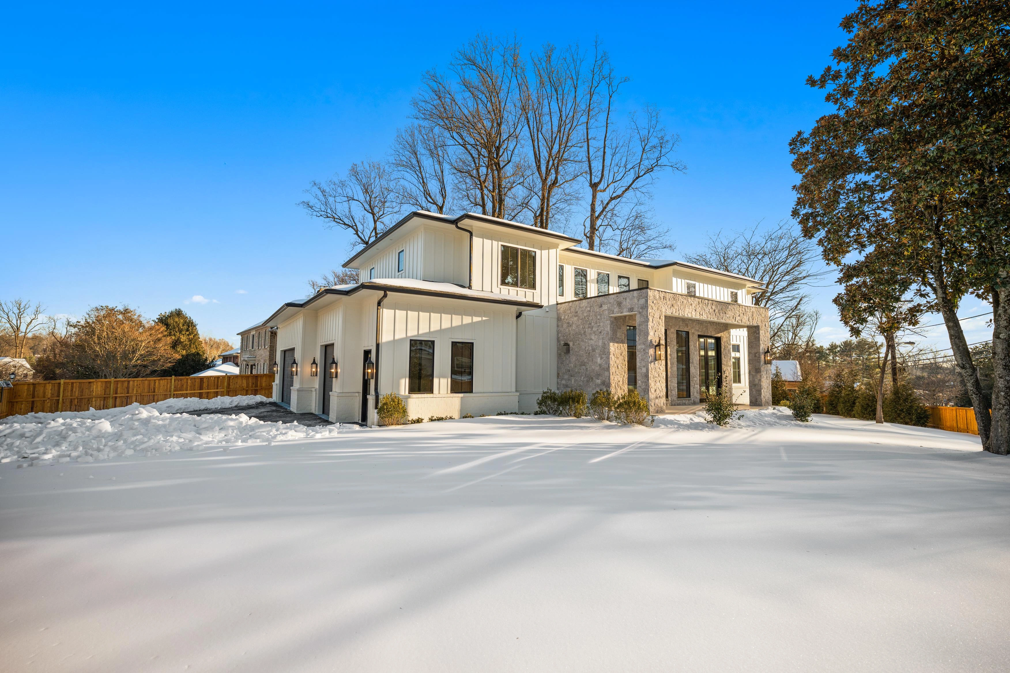 Modern luxury new construction home with stone entry and white siding in snow-covered Bethesda, Maryland