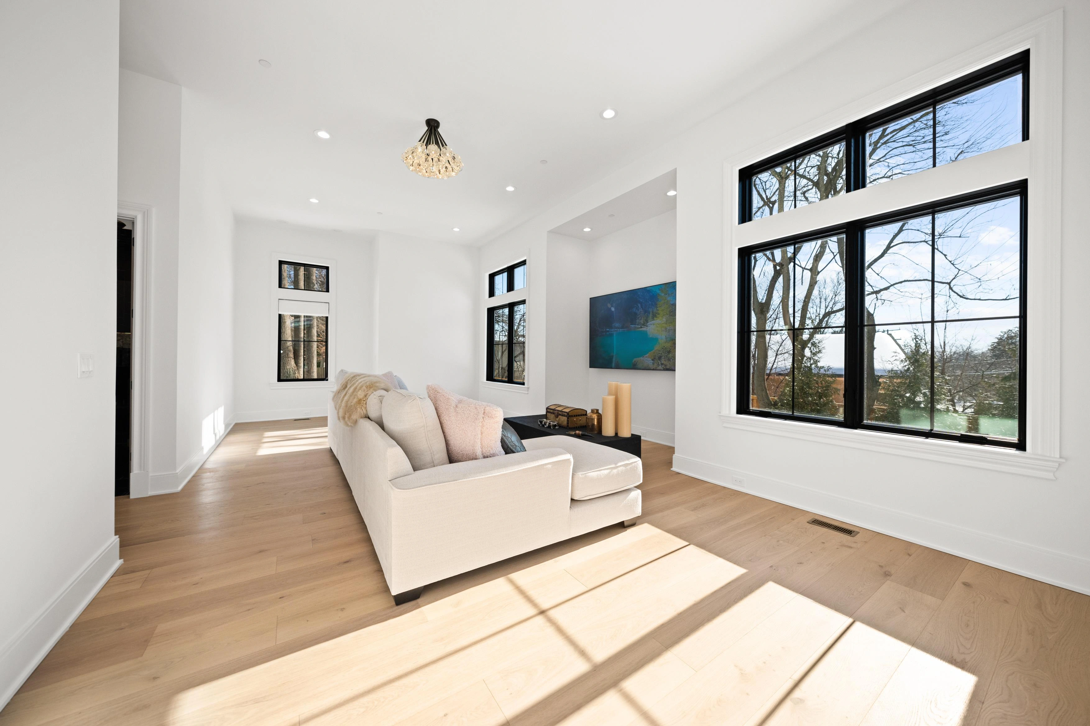 Upstairs family room with built-in TV niche, sofa, and large black-framed windows