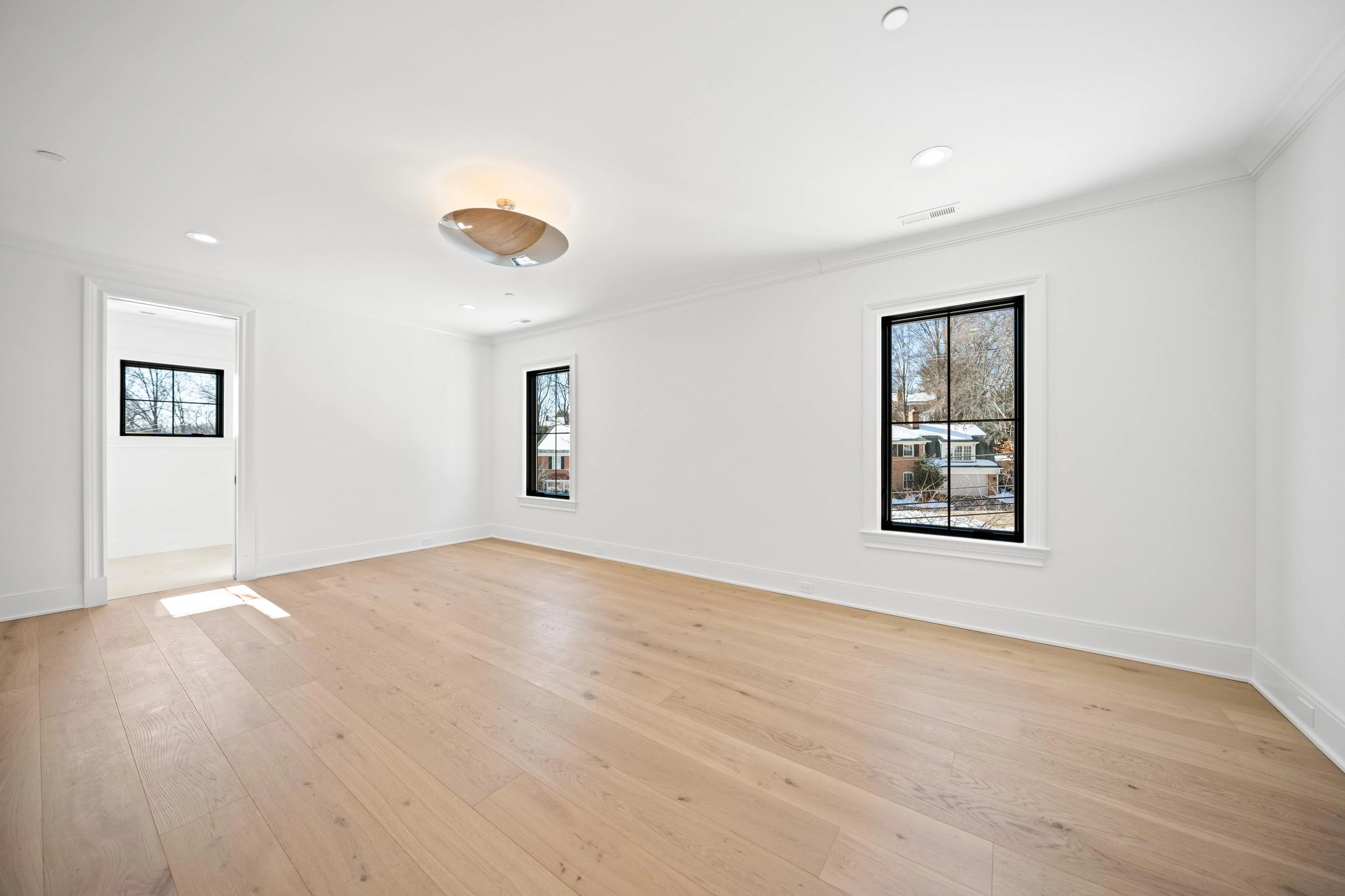 Spacious master bedroom with flush mount ceiling light, hardwood floors, and views to master bathroom