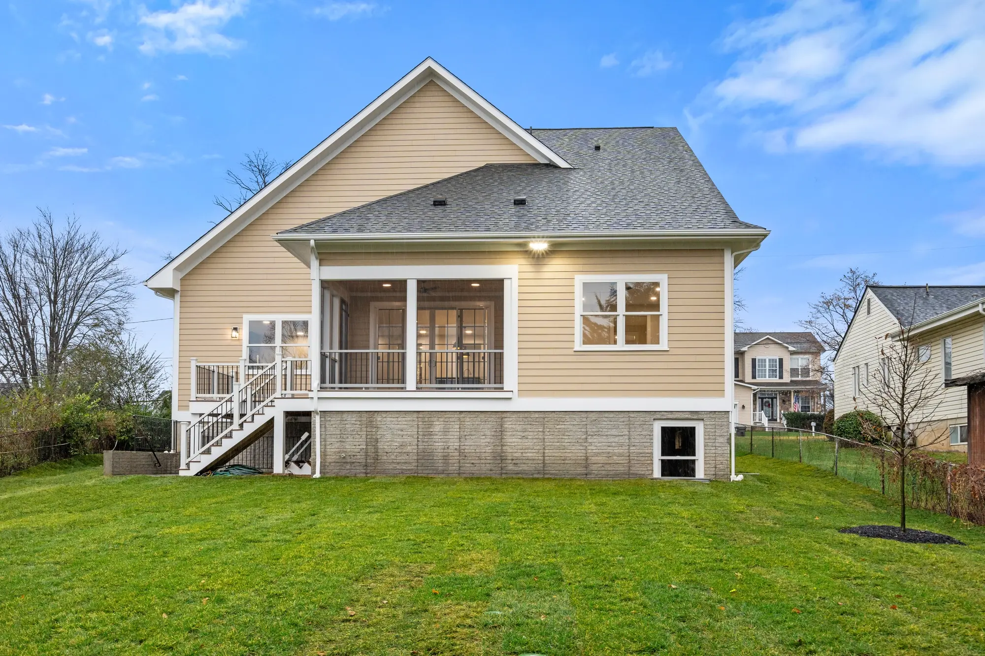 Rear exterior with covered porch, white railing, and green backyard