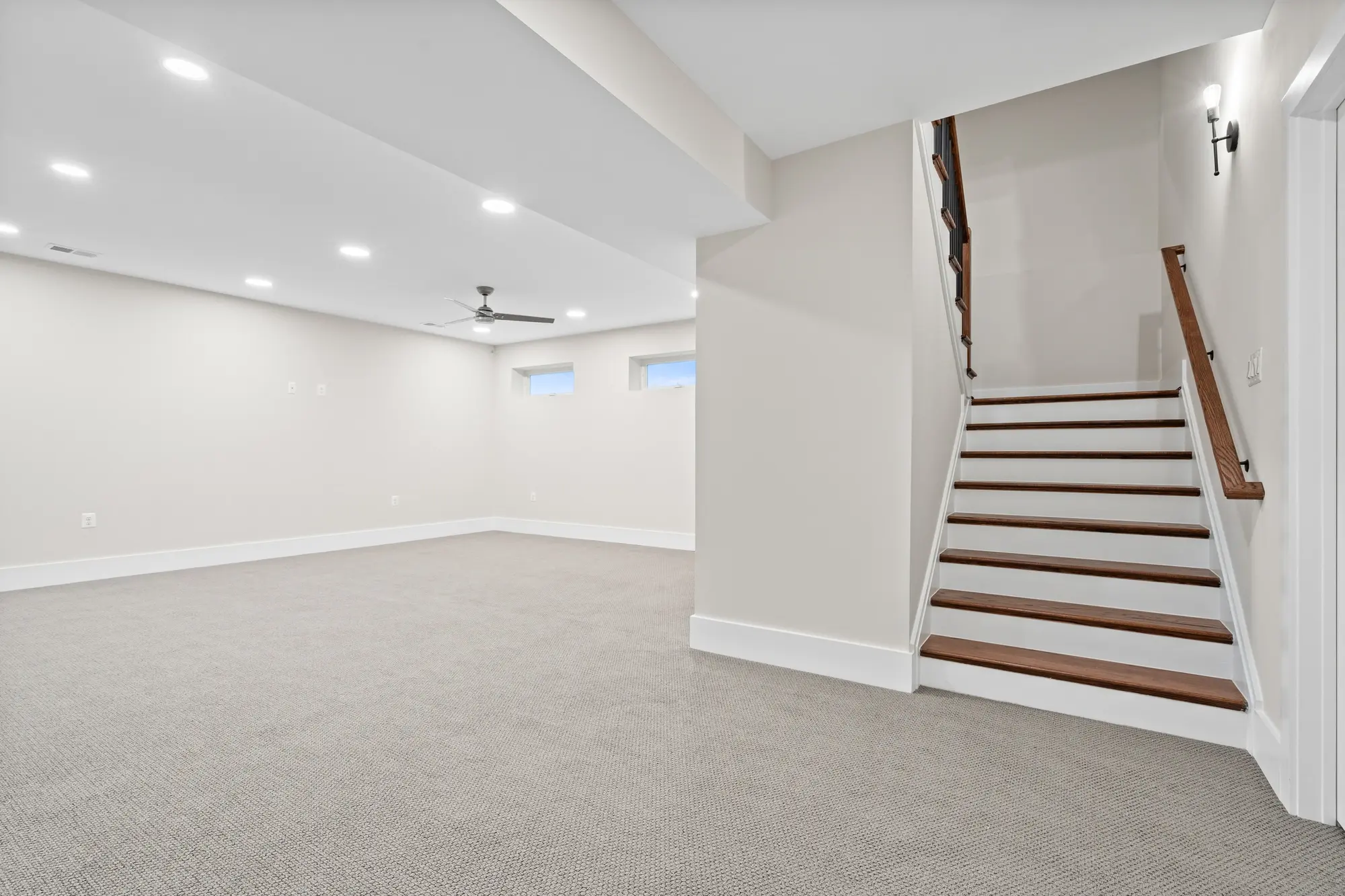 Finished basement with carpet, recessed lighting, ceiling fan, and open staircase