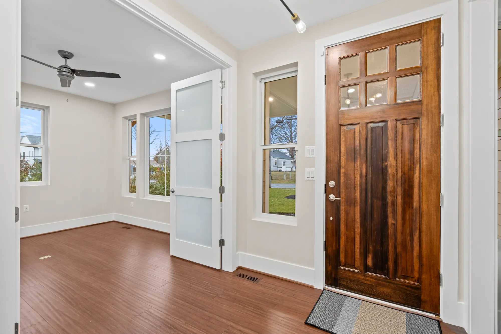 Craftsman-style wood entry door with sidelights and hardwood floors