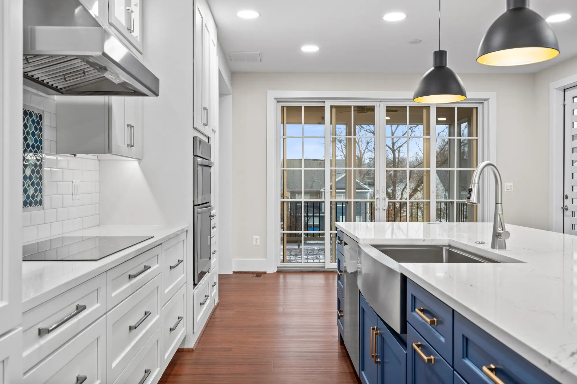 Kitchen island farmhouse sink with marble countertop, pendant lights, and porch view