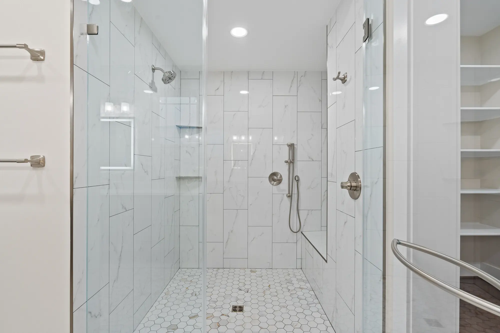 Luxury walk-in shower with marble tile, dual shower heads, and glass enclosure