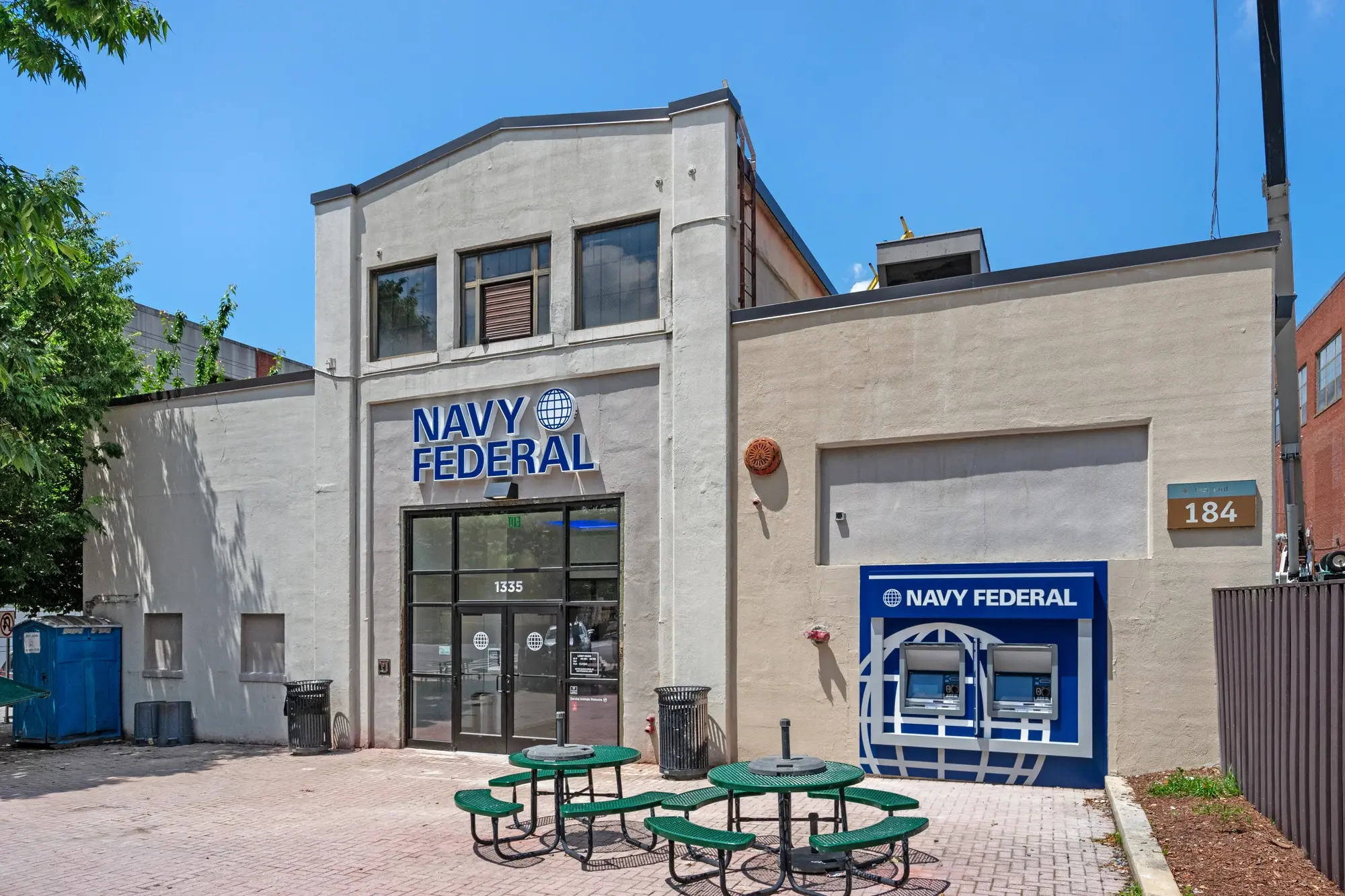 Navy Federal Credit Union branch exterior in daytime showing entrance, signage, ATM station, and outdoor patio seating