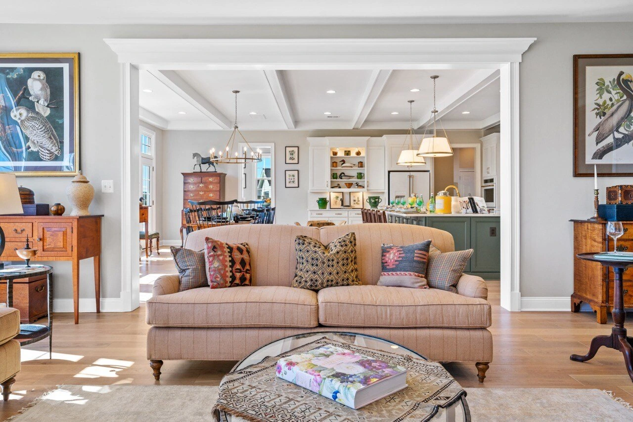 Open-plan living room with sofa, antique furnishings, and view through to kitchen
