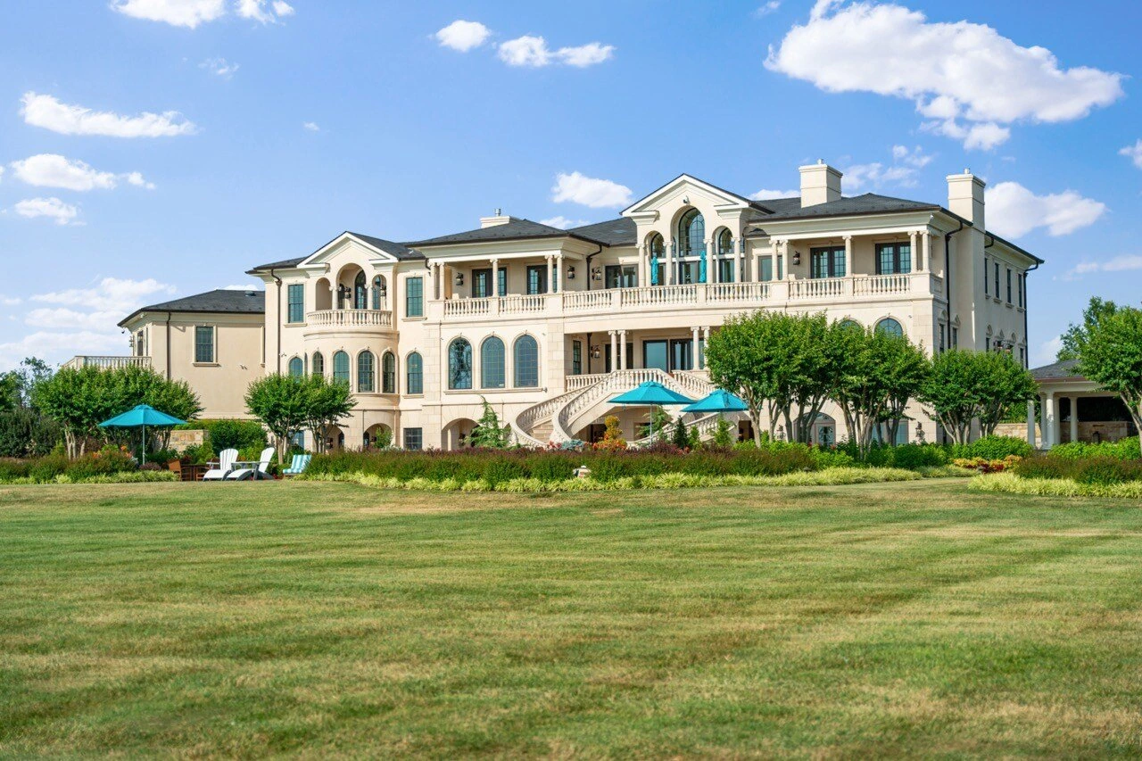 Luxury resort-style pool with hot tub surrounded by lush landscaping and lounge chairs